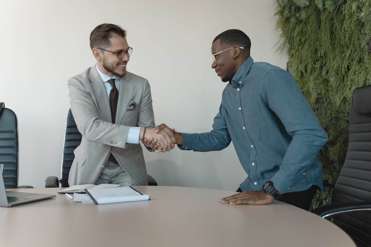 gallery-03 Two men shaking hands during a professional business meeting in a modern office.